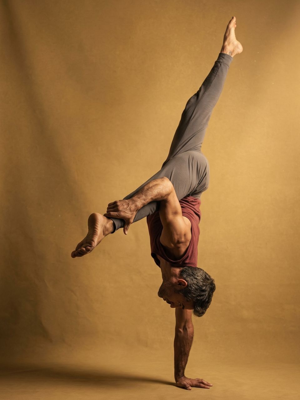 Yuval Oz in a one-arm handstand with split legs during a studio photoshoot